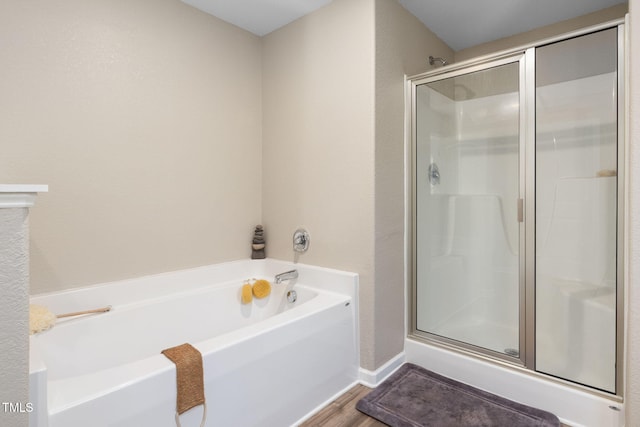 bathroom with independent shower and bath and wood-type flooring