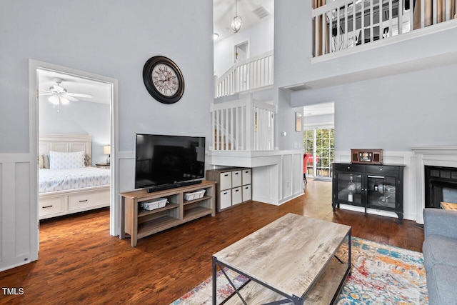 living room with dark hardwood / wood-style floors, ceiling fan, and a towering ceiling