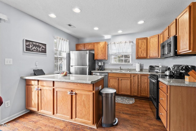 kitchen with stainless steel appliances, sink, a wealth of natural light, and dark hardwood / wood-style flooring