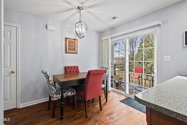 dining space with an inviting chandelier, dark hardwood / wood-style floors, and a textured ceiling