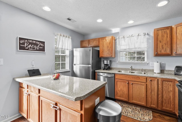 kitchen featuring appliances with stainless steel finishes, dark hardwood / wood-style flooring, sink, and a textured ceiling