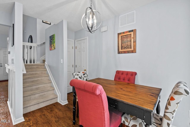 dining area with dark hardwood / wood-style flooring, a chandelier, and a textured ceiling