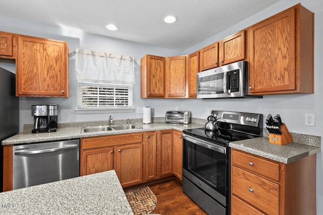 kitchen with appliances with stainless steel finishes, sink, and a textured ceiling