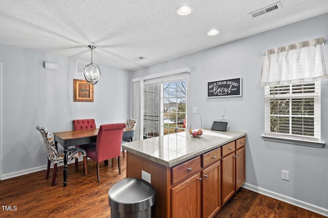 kitchen with decorative light fixtures, dark hardwood / wood-style flooring, a notable chandelier, kitchen peninsula, and a textured ceiling