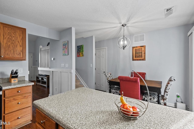 kitchen featuring an inviting chandelier, light stone countertops, hanging light fixtures, and a textured ceiling