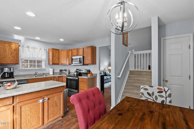 kitchen with dark wood-type flooring, sink, an inviting chandelier, decorative light fixtures, and appliances with stainless steel finishes