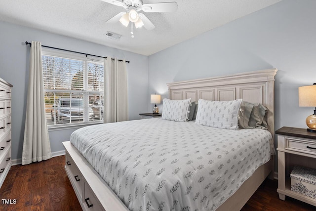 bedroom with ceiling fan, dark wood-type flooring, and a textured ceiling