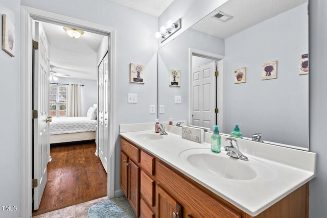 bathroom with vanity, ceiling fan, hardwood / wood-style flooring, and a textured ceiling