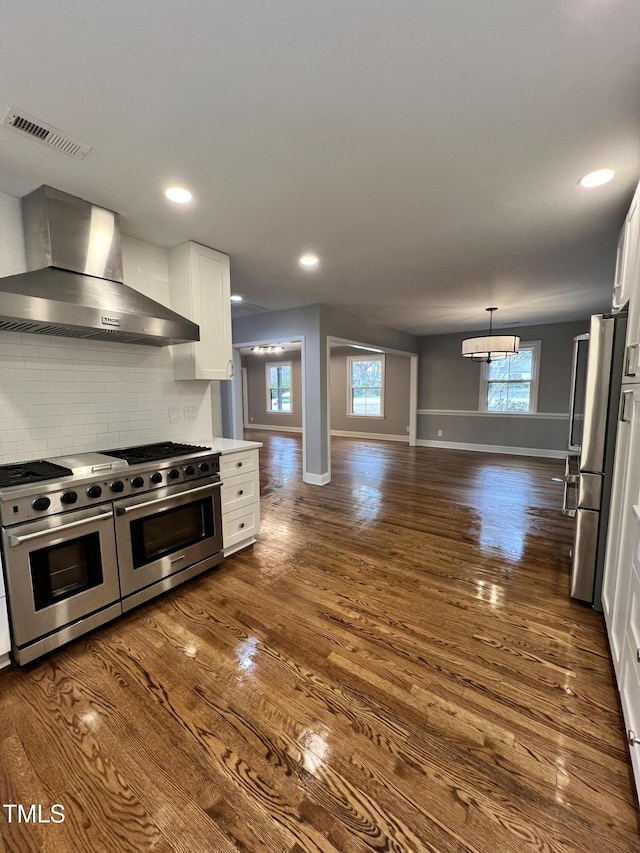 kitchen featuring stainless steel appliances, dark hardwood / wood-style floors, white cabinets, decorative backsplash, and wall chimney exhaust hood