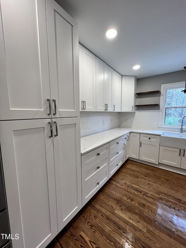 kitchen featuring sink, white cabinetry, dark hardwood / wood-style floors, light stone counters, and tasteful backsplash