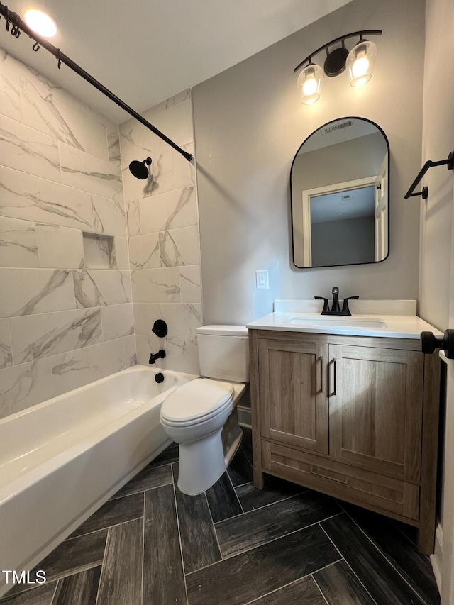 full bathroom with tiled shower / bath, vanity, and toilet