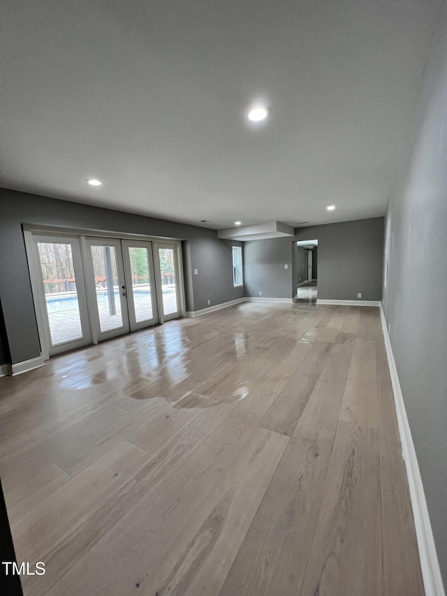 unfurnished living room featuring french doors and light wood-type flooring