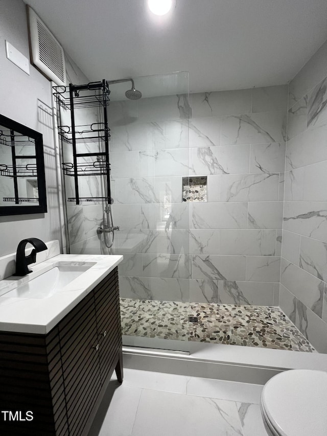 bathroom featuring vanity, toilet, and tiled shower