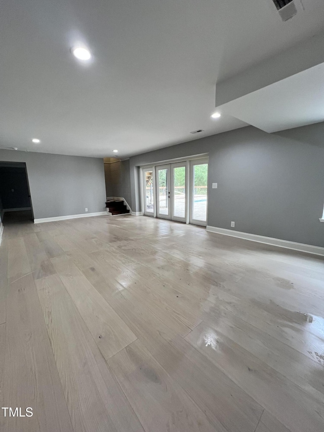 unfurnished living room featuring french doors and light hardwood / wood-style floors