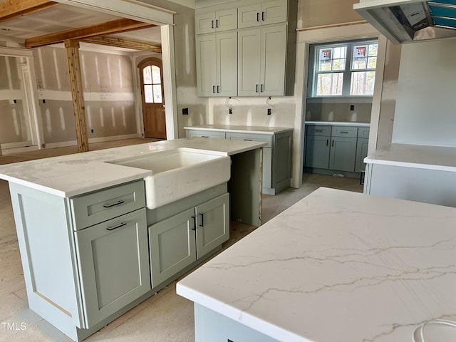 kitchen featuring light stone counters, sink, a healthy amount of sunlight, and premium range hood