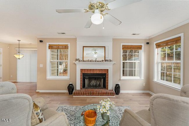 living room with crown molding, a fireplace, light hardwood / wood-style floors, and ceiling fan