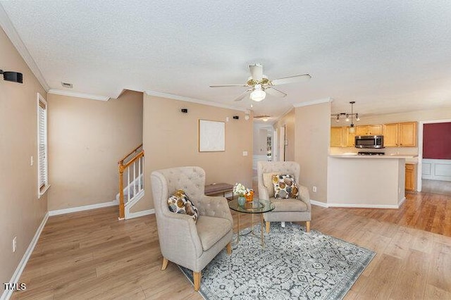 living area with ornamental molding, ceiling fan, a textured ceiling, and light hardwood / wood-style flooring