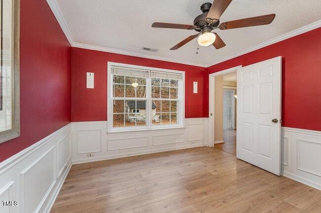 empty room featuring ornamental molding, light hardwood / wood-style floors, and a textured ceiling