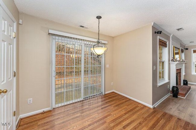 unfurnished dining area featuring a fireplace, wood-type flooring, and a textured ceiling