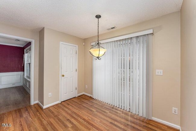 unfurnished dining area with wood-type flooring and a textured ceiling