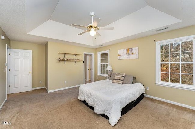 carpeted bedroom featuring ceiling fan and a raised ceiling