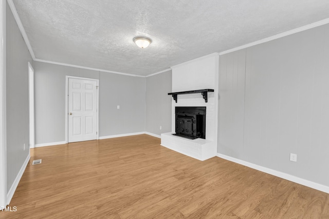 unfurnished living room with a fireplace, light hardwood / wood-style flooring, ornamental molding, and a textured ceiling