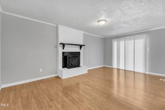 unfurnished living room with ornamental molding, light hardwood / wood-style floors, and a textured ceiling