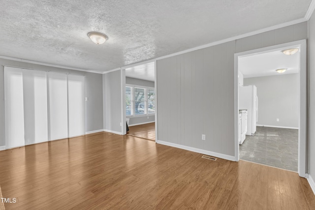 spare room featuring ornamental molding, hardwood / wood-style floors, and a textured ceiling