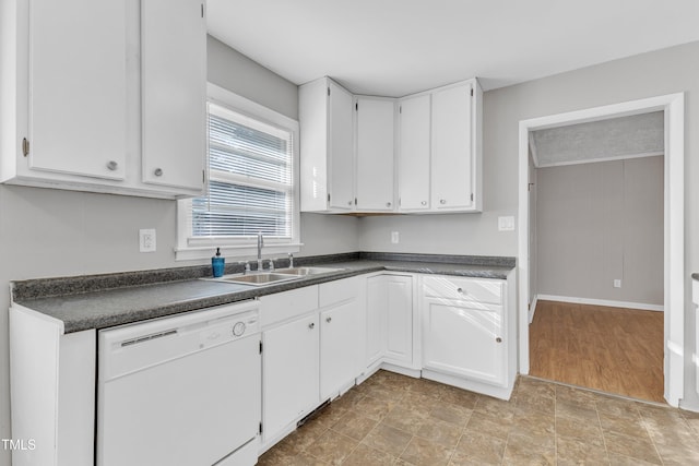 kitchen featuring white cabinetry, sink, white dishwasher, and wood walls