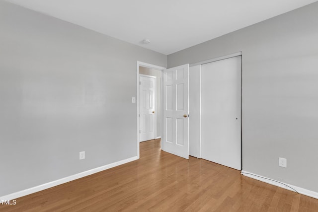 unfurnished bedroom with a closet and light wood-type flooring