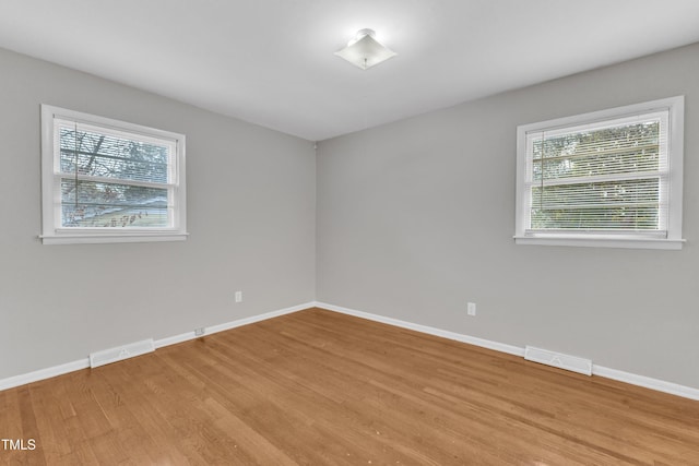 empty room with plenty of natural light and light hardwood / wood-style flooring