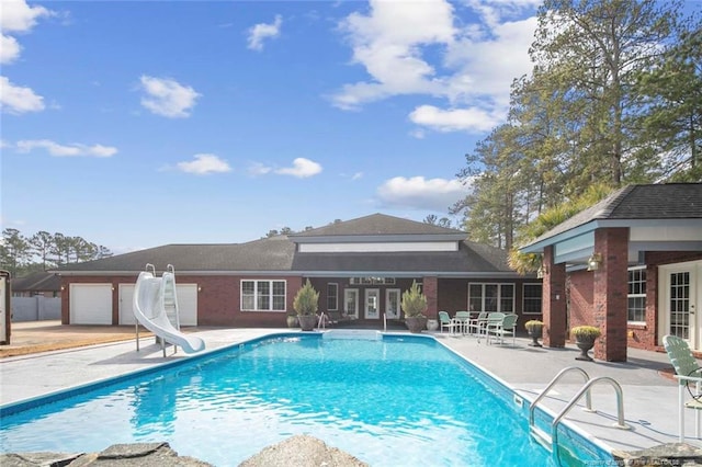 view of swimming pool featuring a water slide and a patio area