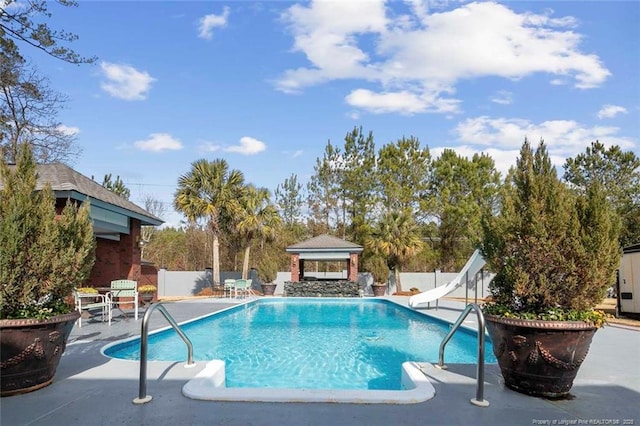 view of swimming pool with a gazebo, a water slide, and a patio area