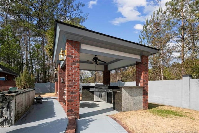 view of patio with grilling area, ceiling fan, and exterior kitchen