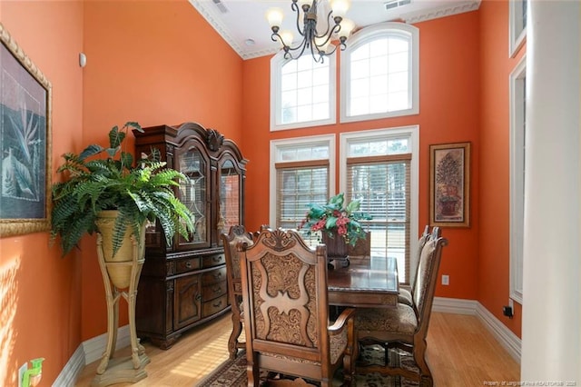 dining area with a high ceiling, a notable chandelier, and light hardwood / wood-style flooring