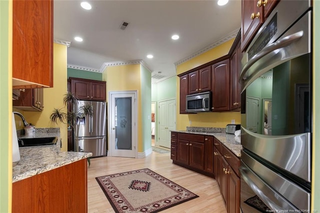 kitchen featuring sink, light wood-type flooring, stainless steel appliances, and light stone countertops