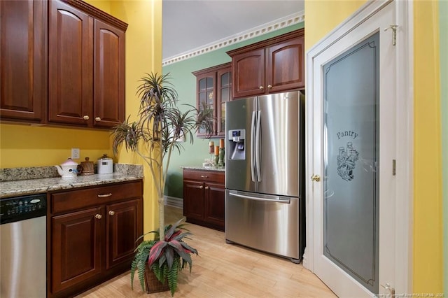 kitchen featuring light stone counters, appliances with stainless steel finishes, and light wood-type flooring