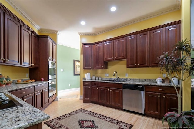 kitchen with light stone counters, sink, light wood-type flooring, and appliances with stainless steel finishes