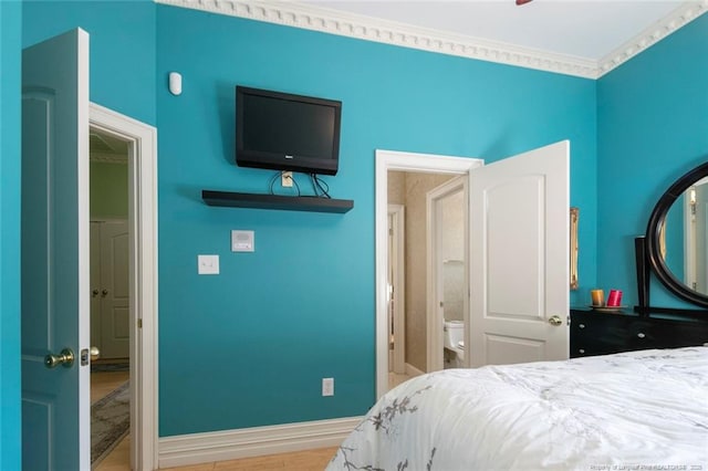 bedroom featuring wood-type flooring, ornamental molding, and ensuite bath