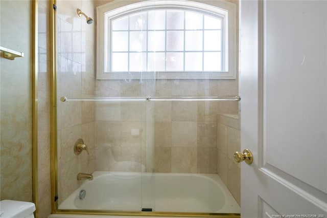 bathroom featuring bath / shower combo with glass door and toilet