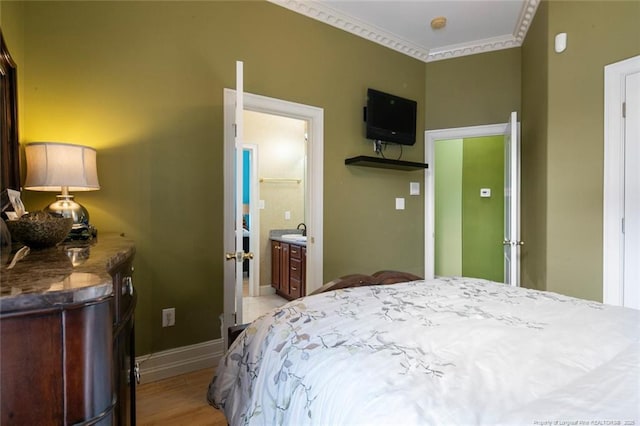 bedroom with connected bathroom, sink, crown molding, and light hardwood / wood-style floors