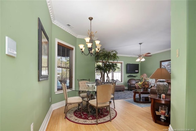 dining space with crown molding, wood-type flooring, and ceiling fan with notable chandelier