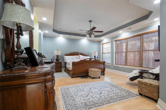 bedroom featuring hardwood / wood-style floors, a tray ceiling, ornamental molding, and ceiling fan