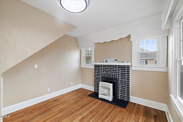 living room featuring hardwood / wood-style flooring, vaulted ceiling, heating unit, and a wood stove