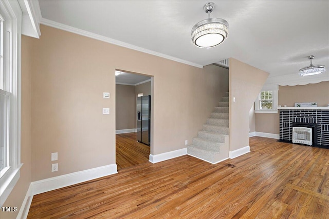 unfurnished living room featuring hardwood / wood-style flooring, ornamental molding, and a tile fireplace