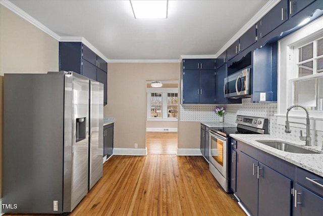 kitchen featuring stainless steel appliances, blue cabinetry, sink, and decorative backsplash