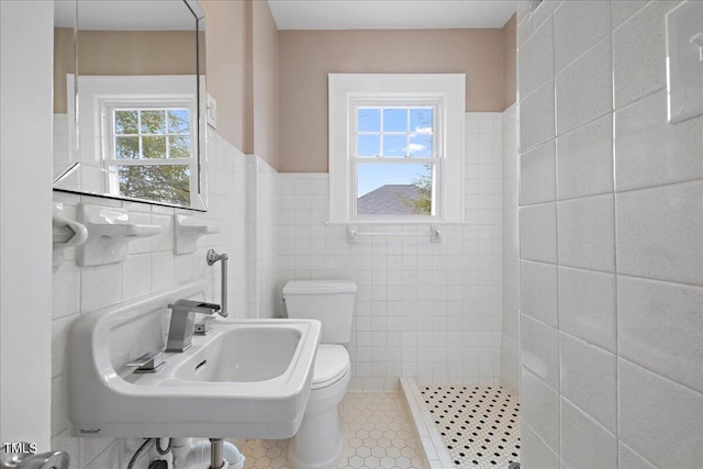 bathroom with toilet, sink, a shower, tile walls, and tile patterned flooring