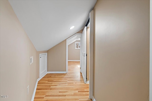 hall with vaulted ceiling and light wood-type flooring