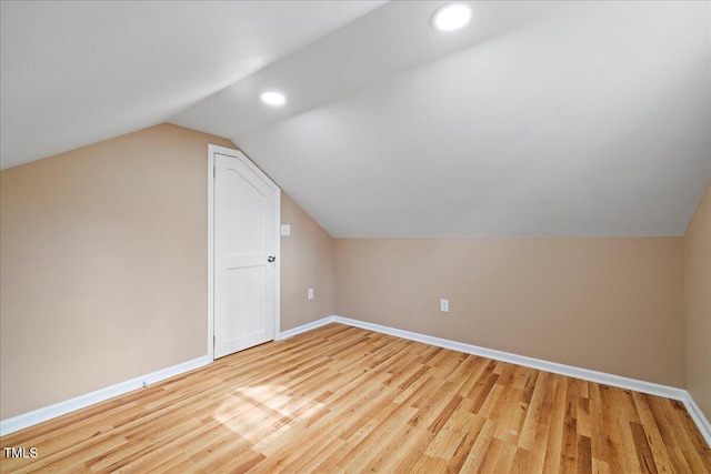 additional living space featuring vaulted ceiling and light hardwood / wood-style floors