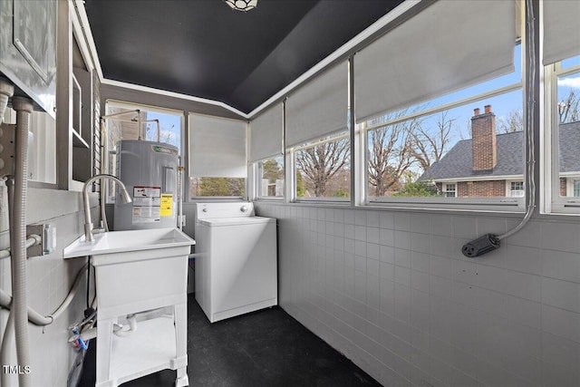 clothes washing area featuring washer / clothes dryer, water heater, and tile walls